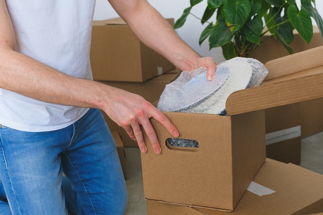 person packing things into a brown moving box